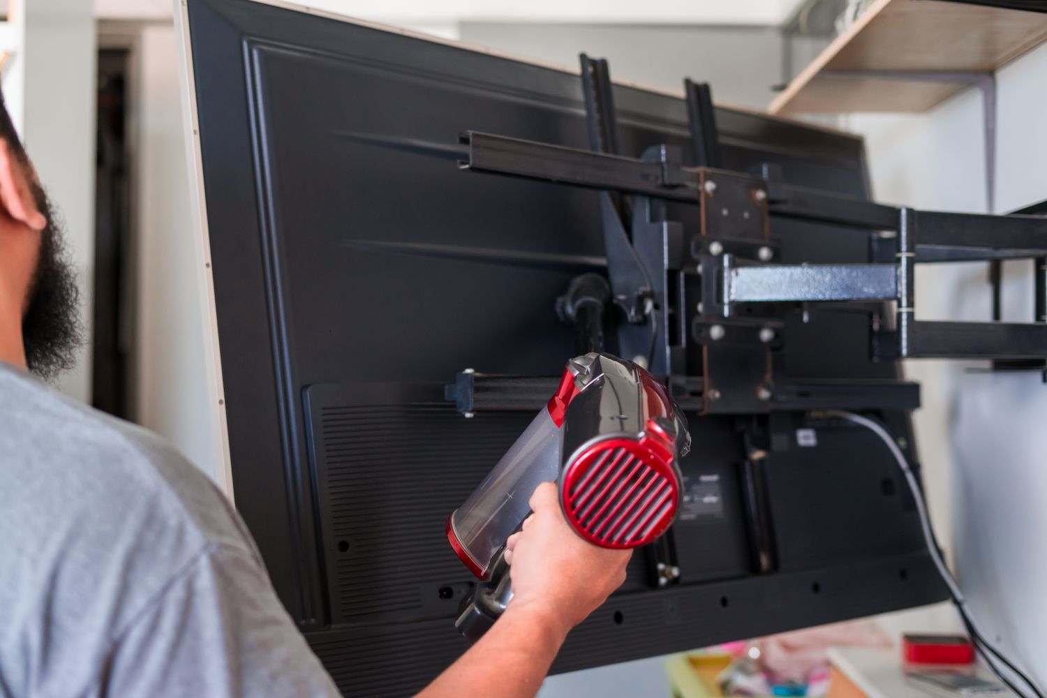 man vacuum cleaning behind television at home
