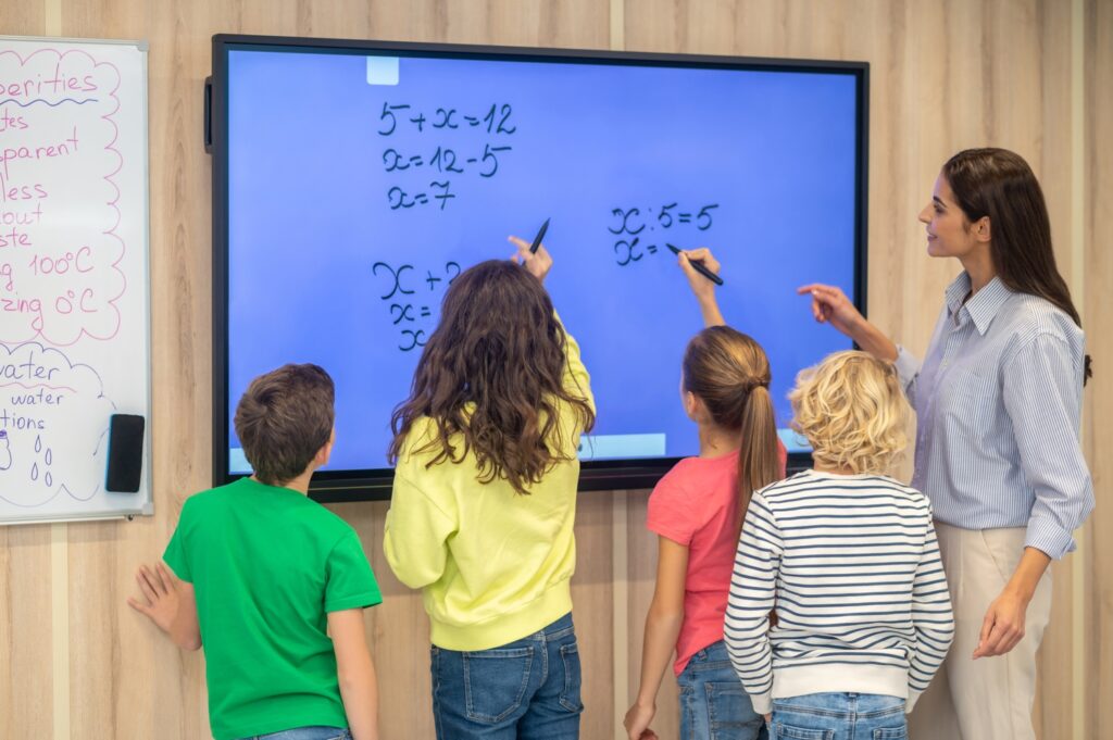 back-view-children-teacher-standing-near-blackboard
